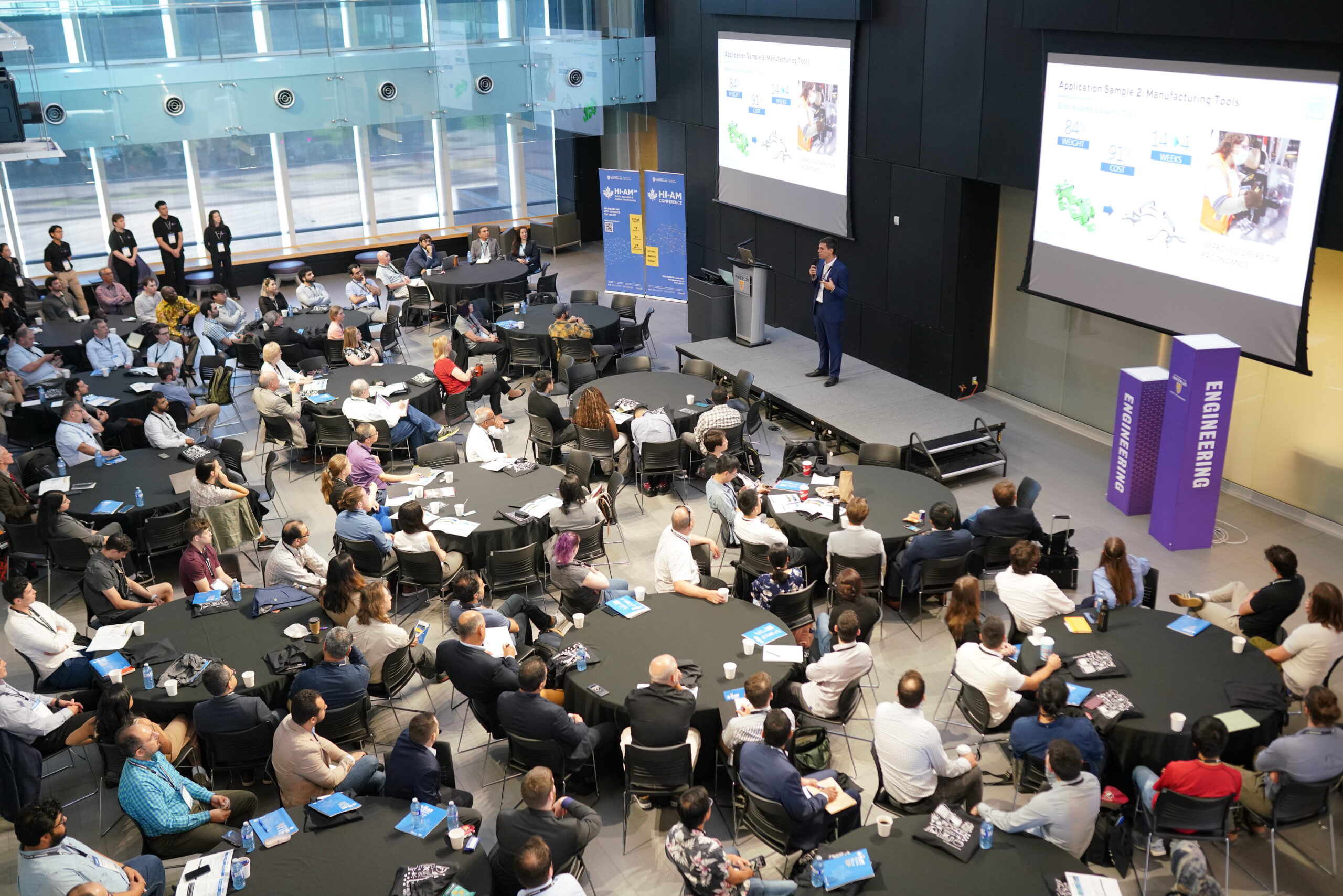 Keynote presenter speaking on stage to a large audience of conference delegates